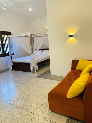 乌纳瓦图纳Oshi villa的一间卧室配有一张床和一个沙发
