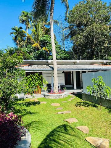 乌纳瓦图纳Oshi villa的一座花园,在一座建筑前种有棕榈树