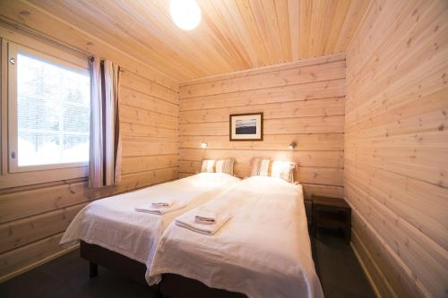 罗瓦涅米Ounasvaaran Lakituvat Chalets的木制客房内的一间卧室,配有一张床