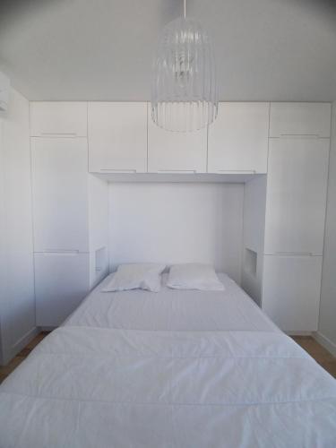 拉格朗德默特Fenestrelle By LGM 57m2 clim, wifi, ménage inclus的白色卧室配有一张床和一个吊灯