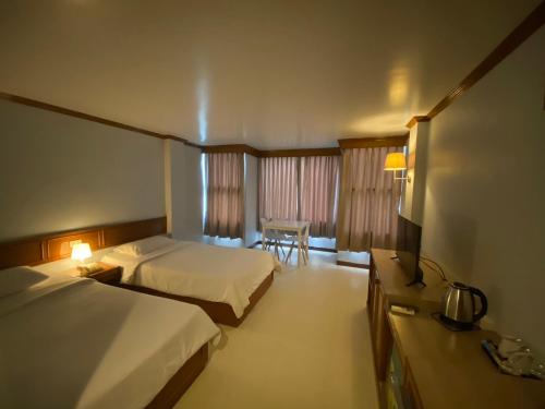Chai BadanNaraigrand Hotel (โรงแรมนารายณ์แกรนด์)的酒店客房设有两张床和一张桌子。