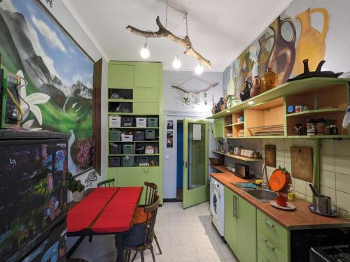 第比利斯礼遇旅舍的厨房配有绿色橱柜和桌子