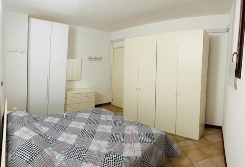 科内利亚诺Appartamento centro storico Conegliano的卧室配有白色橱柜和一张带 ⁇ 子毯子的床