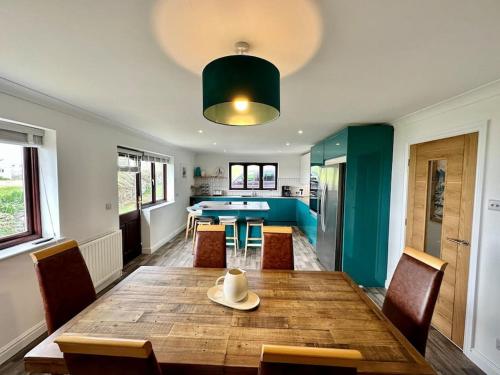 纽基Valley Lodge House - Porth Newquay的一间带木桌和椅子的用餐室