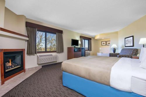 柯林斯堡AmericInn by Wyndham Windsor Ft. Collins的酒店客房设有一张大床和一个壁炉。