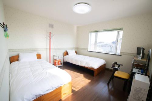 函馆Tomoeドットコム hakodate motomachi的一间卧室设有两张床和窗户。