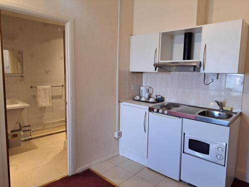 拉格比钻石别墅酒店的小厨房配有白色橱柜和水槽