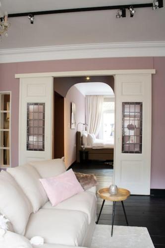 丽兹Suite 137, luxe verblijf midden in de bollenstreek的一间带白色沙发的客厅和一间卧室