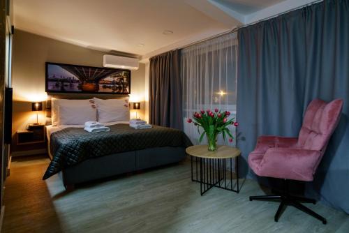 华沙Kamienica no 111a的酒店客房,配有一张床和一张粉红色的椅子