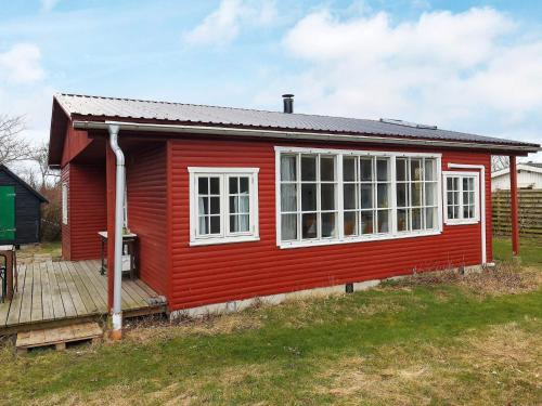 Fakse Ladeplads5 person holiday home in Faxe Ladeplads的红色的房子,设有白色的窗户和甲板