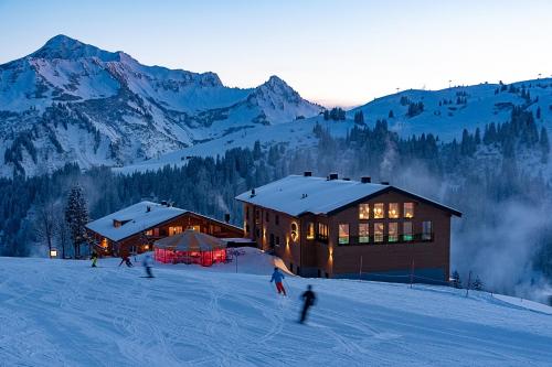 达米尔斯Hotel Walisgaden superior的一群人在小屋前的雪中滑雪