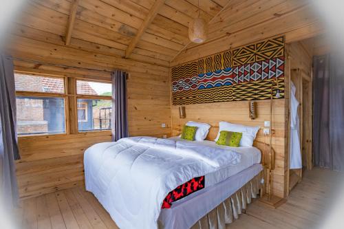 KitabiNyungwe Nziza Ecolodge的木制客房内的一间卧室配有一张大床