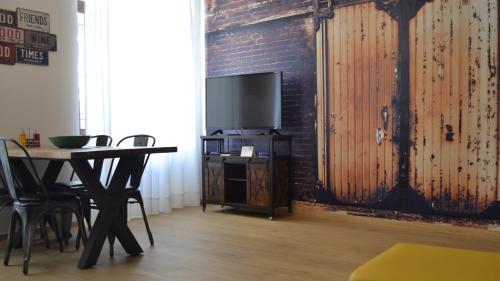 加尔达湖滨RivApartmentsDowntowN Urban的一间设有桌子、电视和砖墙的房间