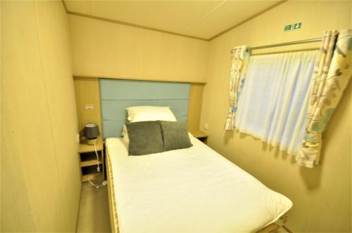 坎伯利Caravan by Camber Sands 2的一个小房间的小床,设有窗户