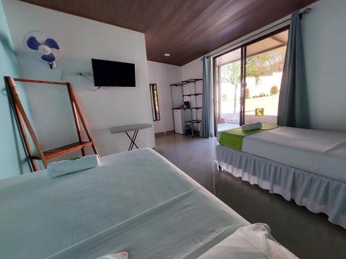 塔马林多Hotel Casa Carlota Tamarindo的客房设有两张床、一台电视和一扇窗户。
