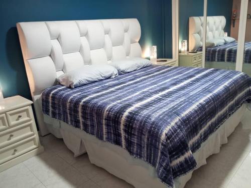 加拉加斯CALIFORNIA SUITE的一间卧室配有一张带蓝白色毯子的床