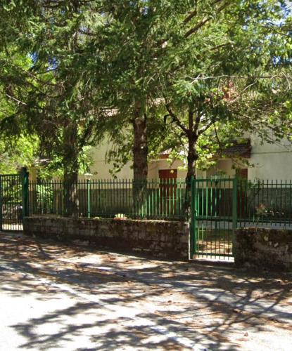 CuturaWhite’s House的树木繁茂的房屋前的绿色围栏