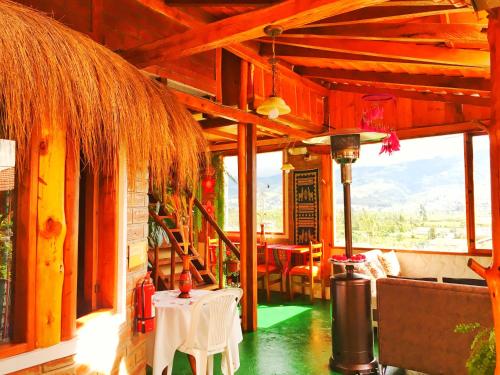 奥塔瓦洛Hospedaje Vertientes del Imbabura的餐厅设有桌椅和大窗户。