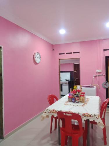 Kampong Tanjong IpohKuntum Cottage Bad & Breakfast的用餐室设有粉红色的墙壁和一张带红色椅子的桌子