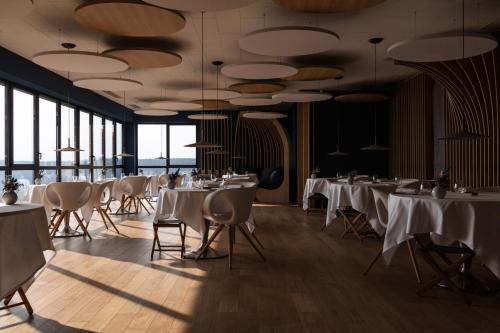 伊苏瓦尔Hôtel & Restaurant Origines par Adrien Descouls - Teritoria的餐厅设有白色的桌椅和窗户。