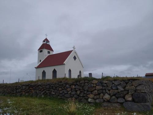 ModrudalurFjalladýrð Hostel的白色的教堂,有红色的屋顶和石墙