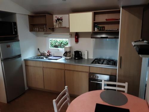 加斯泰mobil home 3chambres tout confort的小厨房配有桌子、水槽和炉灶。