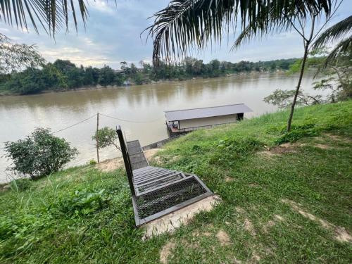 淡马鲁Chalet Terapung Laman Tok Ayah Temerloh的坐在河边的长凳