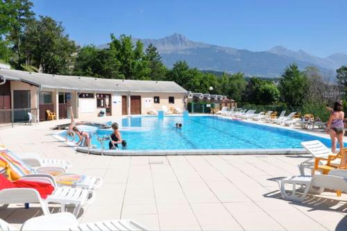 绍尔日Vue imprenable sur Lac de Serre-Ponçon à Chorges : appt prestige 8 pers的一座带椅子和人手的大型游泳池