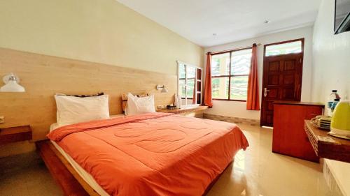 纳闽巴霍巴约中心酒店＆餐厅的一间卧室配有一张带橙色毯子的床