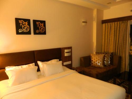 普里Pramod Convention & Beach Resorts的配有一张床和一把椅子的酒店客房