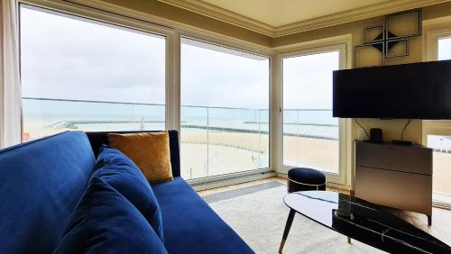 奥斯坦德Maui - zeezichtappartement te Oostende的客厅设有蓝色的沙发和大窗户