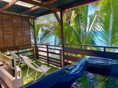 圣安德烈Les îlots du soleil levant的一座带热水浴池和椅子的别墅,并种植了棕榈树