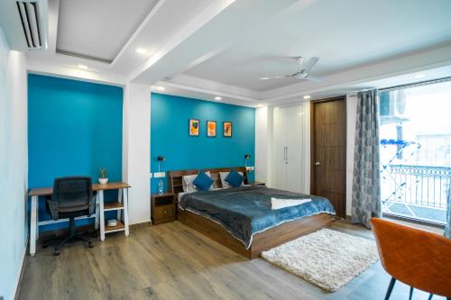古尔冈FlxHo Uno - Serviced Apartment & Rooms - Golf Course Road的一间卧室设有蓝色的墙壁、一张床和一张书桌