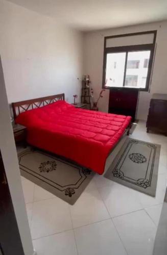 Oulad YakoubAppartement的窗户客房内的一张红色的床