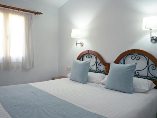 英格兰海滩Bungalows Los Almendros - Exclusive Vacation Club的一间卧室配有一张带两个蓝色枕头的床
