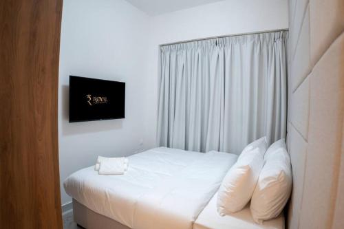 Al QurayyahMasdar Mirage Oasis 2BR Duplex with Pool Access的一间卧室配有带白色床单和枕头的床。