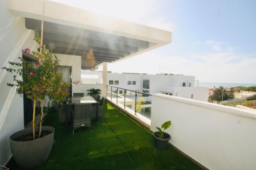 托雷德本纳贾尔邦Atico con piscina, golf, vistas al mar的大楼内的阳台种植了绿草和植物