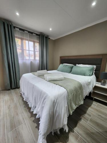 哈里史密斯Cozy and Comfort的一间卧室配有一张带白色床单和绿色枕头的大床。
