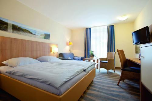 诺德奈Inselhotel Bruns的酒店客房配有一张床、一张书桌和一台电视。