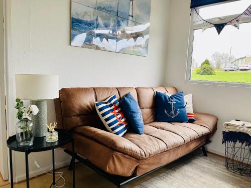 Brading“SEA HEAVEN “ chalet in Sandown Bay Holiday Park的客厅里配有带蓝色枕头的棕色沙发
