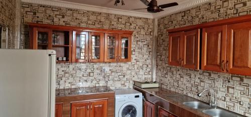 库马西OKF OBOUBA APARTMENT的厨房配有木制橱柜、洗衣机和烘干机