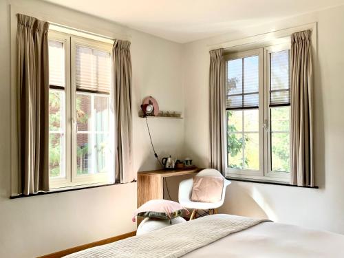 迪尔森-斯托科姆农德迪酒店的一间卧室设有2扇窗户和1张床及椅子