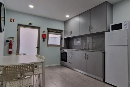 埃斯平霍Casa de Férias_As Oliveiras III的厨房配有桌子和白色冰箱。