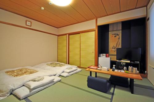Kurihara安倍附楼酒店的配有两张床铺、一张桌子和一台电视机的客房