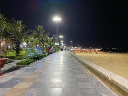 归仁Hotel Hoàng Hưng Quy Nhơn的一条棕榈树的步道和夜间的街灯