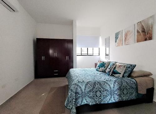 普拉亚卡门Casa en privada con alberca, Excelente para vacaciones y descanso的一间卧室配有一张带蓝色毯子的床