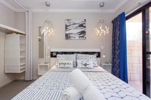 珀斯Bambino 438的一间卧室配有白色的床、蓝色窗帘和吊灯