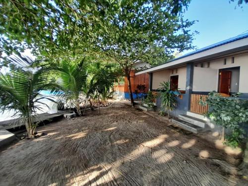 美娜多Bunaken Sunrise Beach的一座房子前面的庭院,里面种有棕榈树