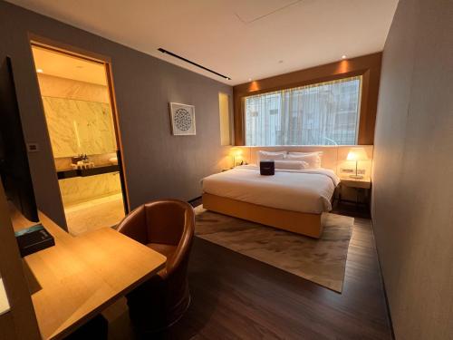 新加坡Naumi Hotel的一间卧室配有一张床、一张书桌和一个窗户。