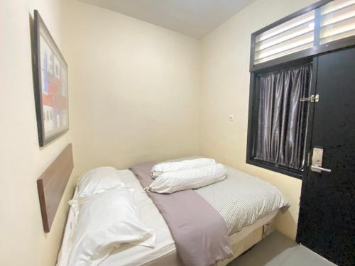 BitungDe Homestay Mitra RedDoorz Bitung的一间卧室配有一张带白色床单的床和一扇窗户。